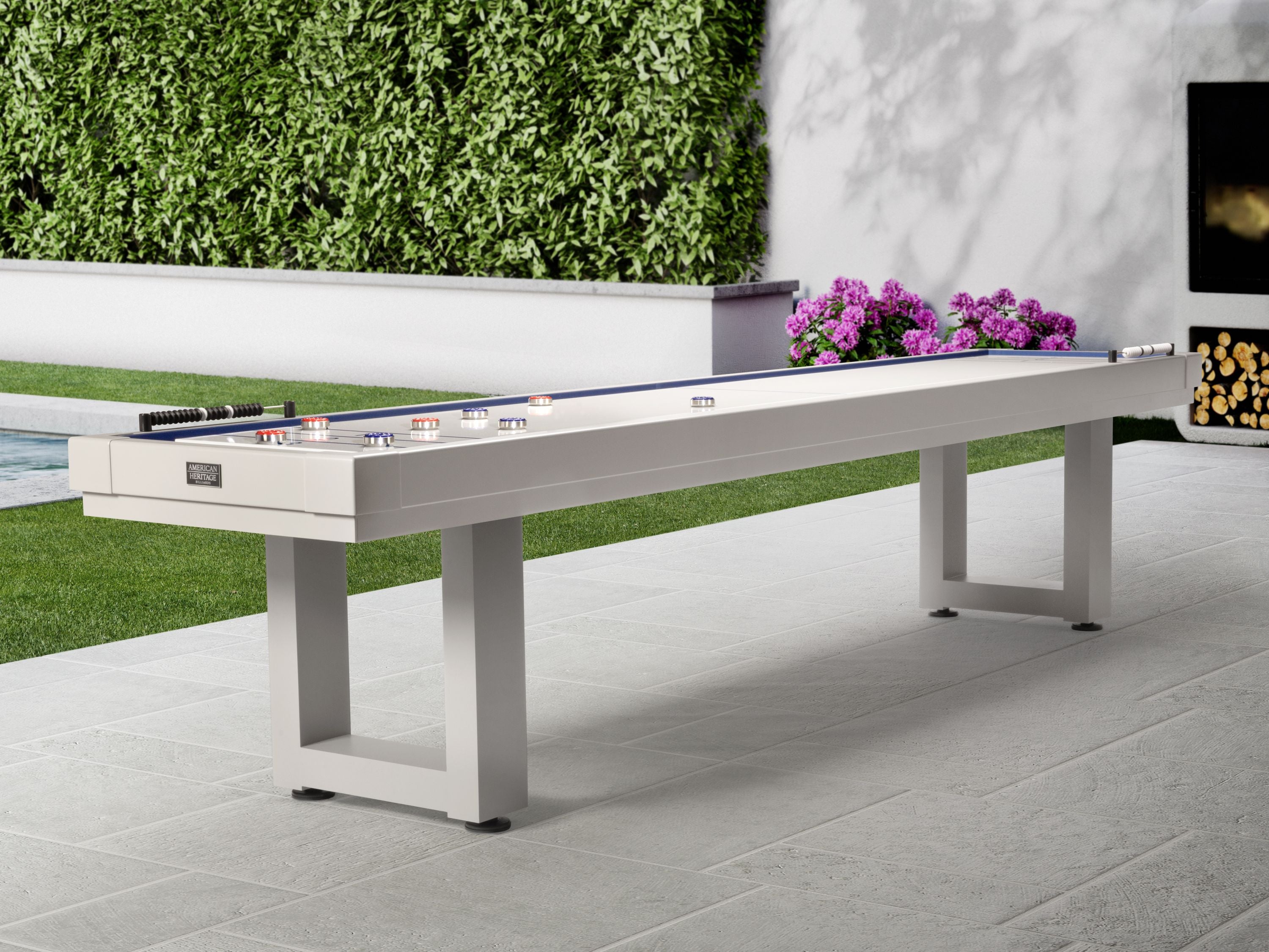 American Heritage Lanai 9' Outdoor Shuffleboard Table in Pearl White on a patio with greenery.