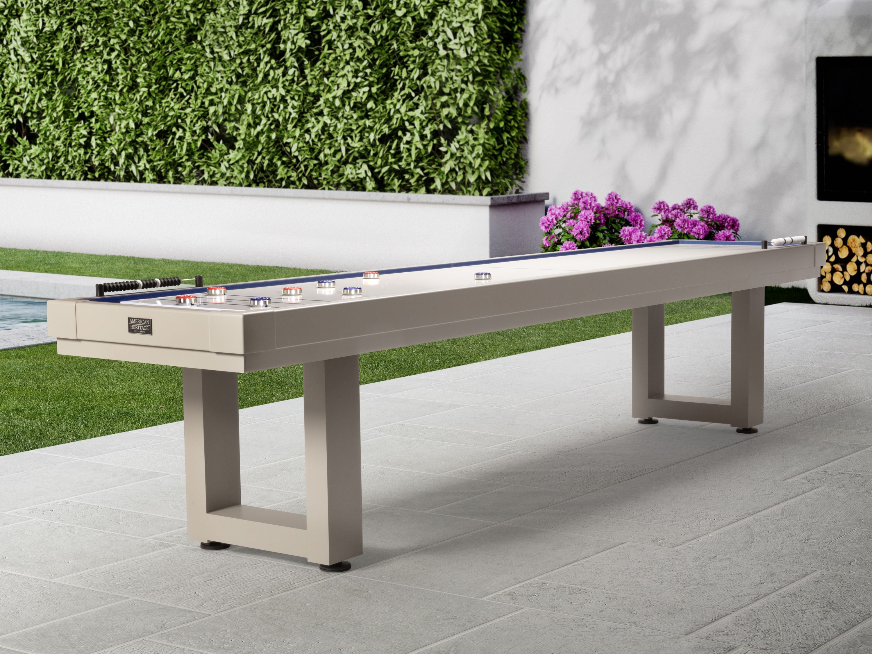American Heritage Lanai 9' Outdoor Shuffleboard Table in Oyster Grey on a patio with greenery.