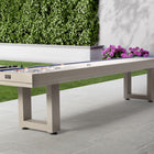 American Heritage Lanai 9' Outdoor Shuffleboard Table in Oyster Grey on a patio with greenery.